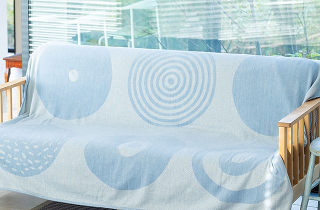 ソファに掛けた水色のライトコットンのブランケット