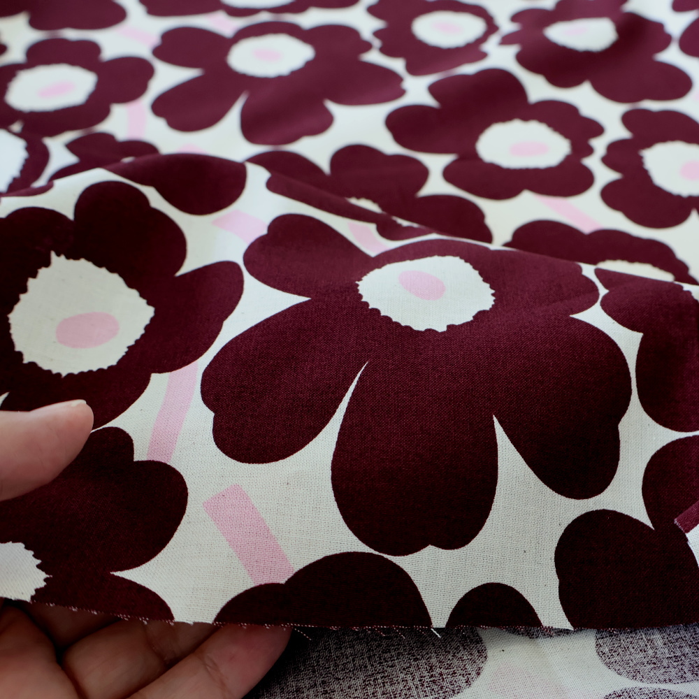 marimekko Mini Unikko ダークレッド×ライトピンク 生地アップ 手に持った様子｜厚みと風合いがわかる写真